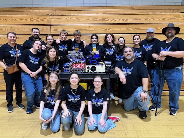 FTC 25619 Nova Pyra team members surrounding their robot 'Bullfrog' with their trophies after their successes at the 2024-2025 FTC LA Qualifier 1 at Hammond Crossroads